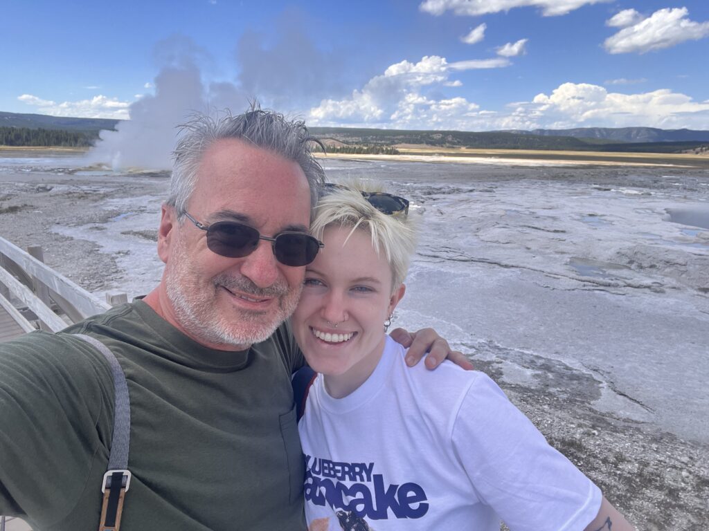Me and Becca, selfie on the boardwalk, geyser erupting behind us